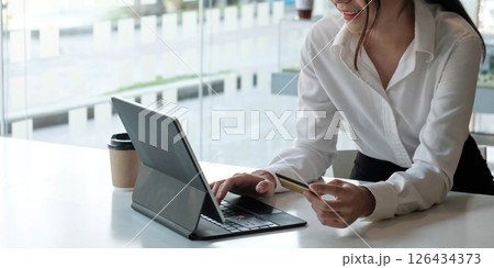 Young Asian businesswoman enjoy shopping online using credit card at a coffee shop. 126434373