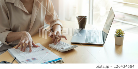 Business woman working in finance and accounting Analyze financial budget with calculator and laptop computer in the office 126434584