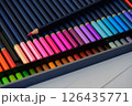 Two rows of colored pencils with a sharp point on red pencil in pencil case 126435771