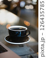 Delicious Black Coffee on a Table Surrounded by a Warm, Cozy Cafe Ambiance and Atmosphere Delicious Black Coffee on a Table Surrounded by a Warm, Cozy Cafe Ambiance and Atmosphere 126435785
