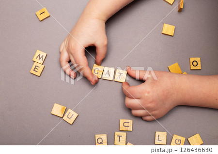 child hand hands collecting word cat from wooden cubes on gray background. 126436630
