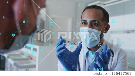 Holding vaccine vial, doctor in mask with medical icons image over scene Holding vaccine vial, doctor in mask with medical icons image over scene 126437565