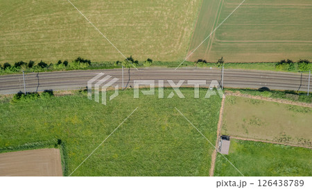 Stunning aerial view of railway tracks through lush green fields, showcasing natures beauty 126438789
