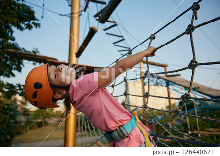 School girl climbing in adventure rope city park on summer day 126440621
