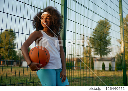 Portrait of attractive female basketball player with ball at sport ground 126440651