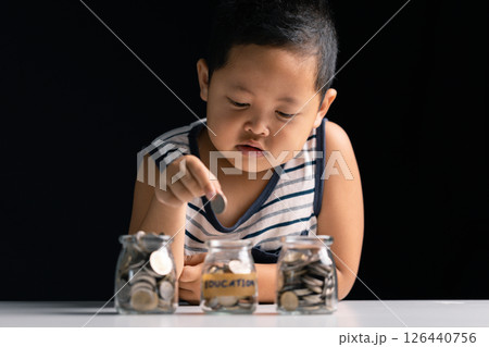 Young boy learns to save money by studying finance, collecting coins, and understanding the importance of investment and saving for children. boy, save, money, study, children, person, coin, finance. Young boy learns to save money by studying finance, collecting coins, and understanding the importance of investment and saving for children. boy, save, money, study, children, person, coin, finance. 126440756