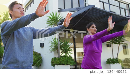 Image of spots of light over biracial couple practicing yoga by house Image of spots of light over biracial couple practicing yoga by house 126440921
