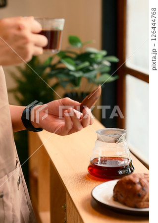 Close up of man brewing coffee with pour over method using a glass dripper in a kitchen 126444768