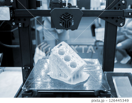 Prototype of car engine printed on 3D printer from molten white plastic on working surface 3D printer. Three-dimensional model. Additive modeling technology. Modern new printing industry. Blue color Prototype of car engine printed on 3D printer from molten white plastic on working surface 3D printer. Three-dimensional model. Additive modeling technology. Modern new printing industry. Blue color 126445349