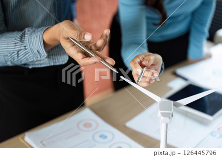 ESG Business Collaboration. Professionals discussing renewable energy solutions with wind turbine model. 126445796
