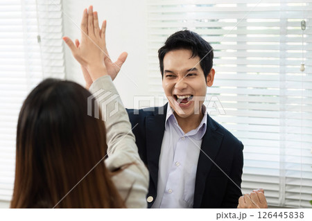 Celebrating Success. Team members high-fiving after achieving a milestone in the office. 126445838