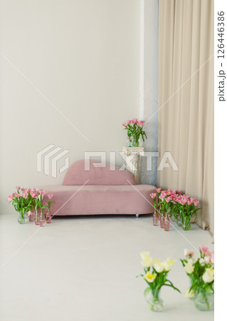 An elegantly designed interior showcases a minimalist pink sofa that is beautifully complemented by an arrangement of fresh flowers, creating a harmonious and inviting atmosphere for relaxation An elegantly designed interior showcases a minimalist pink sofa that is beautifully complemented by an arrangement of fresh flowers, creating a harmonious and inviting atmosphere for relaxation 126446386