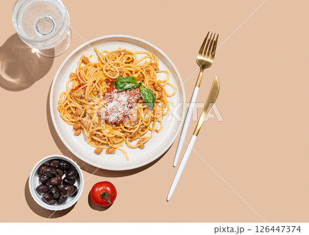 Spaghetti bolognese with tomato sauce, basil and parmesan cheese on beige background Spaghetti bolognese with tomato sauce, basil and parmesan cheese on beige background 126447374