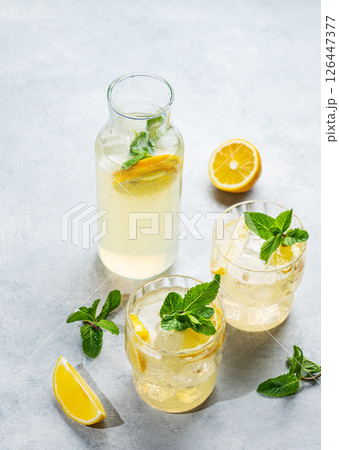 Fresh lemonade with lemon, mint and ice. Two glasses of citrus mojito on a light background Fresh lemonade with lemon, mint and ice. Two glasses of citrus mojito on a light background 126447377