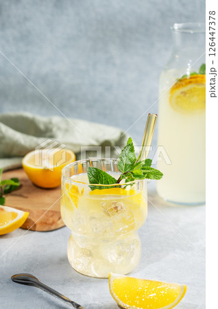 Fresh drink lemonade with lemon, mint and ice in glass on a light background with bottle Fresh drink lemonade with lemon, mint and ice in glass on a light background with bottle 126447378