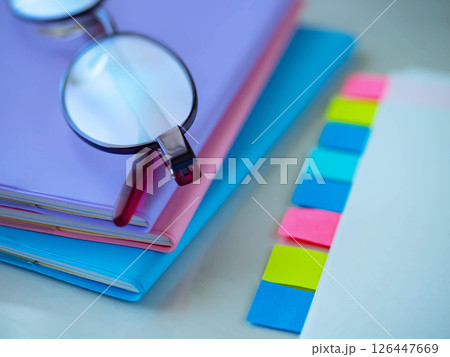 テーブルに置かれた書類と手帳とメガネ 126447669
