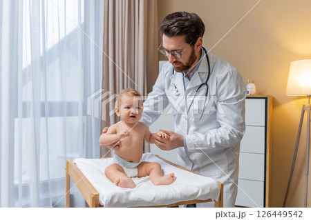 Doctor examining a little baby boy in his office and looking concentrated 126449542