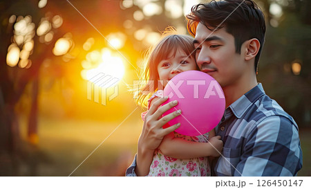 Young father holding his daughter in his arms against the bright sun. Concept of parent-child relationship and Father's Day celebration Young father holding his daughter in his arms against the bright sun. Concept of parent-child relationship and Father's Day celebration 126450147