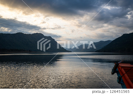 Wake trail behind ferry moving across Teletskoye lake in Altai Russia. Tranquil water surface with distant shoreline and mountains 126451565