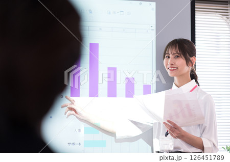 スクリーンの前でプレゼンテーションするカジュアル衣装の若い女性 126451789