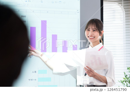 スクリーンの前でプレゼンテーションするカジュアル衣装の若い女性 スクリーンの前でプレゼンテーションするカジュアル衣装の若い女性 126451790