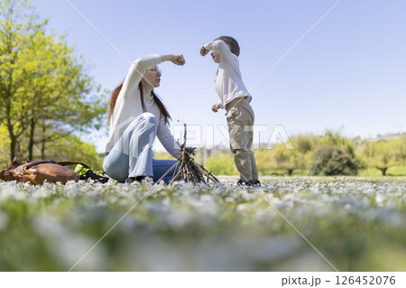 Mother and son building a small bonfire in a field of flowers 126452076