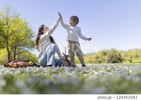 Mother and son giving high five in blooming meadow by campfire Mother and son giving high five in blooming meadow by campfire 126452081