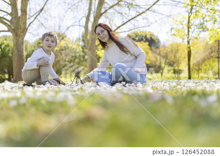 Mother and son building tiny stick house in spring meadow 126452088