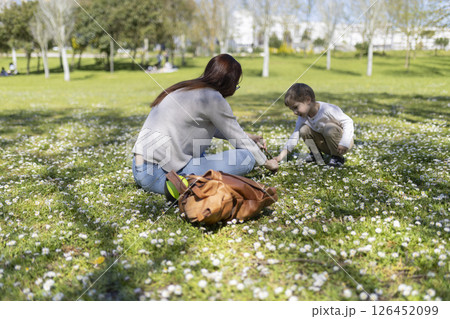 Mother and daughter picking daisies in a sunny park 126452099