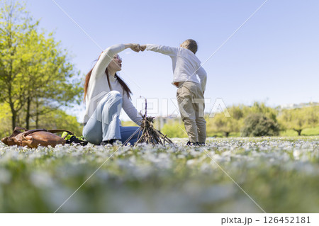 Mother and son building a small bonfire in a field of flowers 126452181
