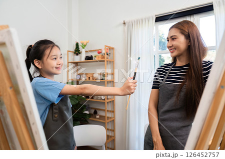 Family time as a girl shares a paintbrush with her mom 126452757