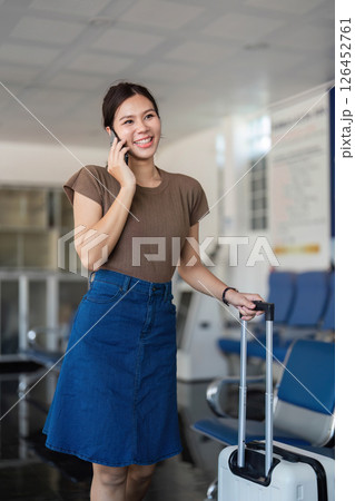 Travel woman at airport checking phone while waiting for flight Travel woman at airport checking phone while waiting for flight 126452761
