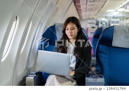 Business travel: Young woman concentrating while using a laptop on a flight 126452764