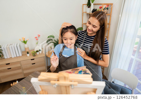 Family time creating art: Engaging mother-daughter painting moment 126452768