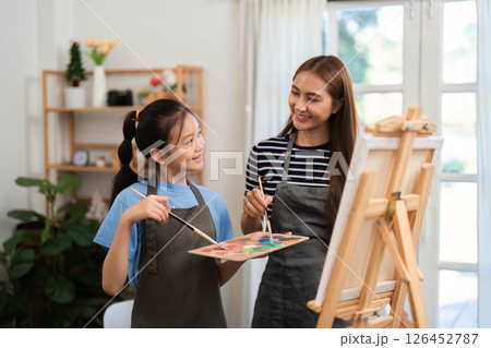 Creative bonding activity: Mother and daughter painting together in a cozy environment Creative bonding activity: Mother and daughter painting together in a cozy environment 126452787