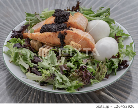 Homemade salad with Grilled salmon fillets, Boiled egg and Croutons topping Caviar on plate. 126452926