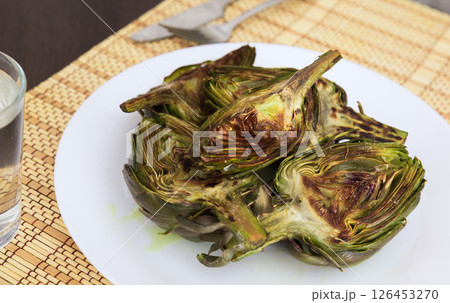 Cooked fried halves artichokes on white plate 126453270