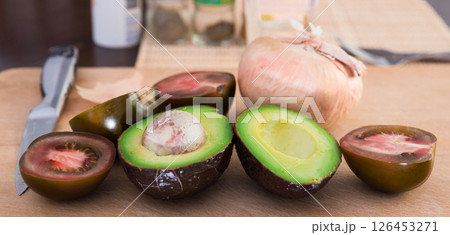 Vegetables black tomatoes, avocado and onions on wooden board 126453271