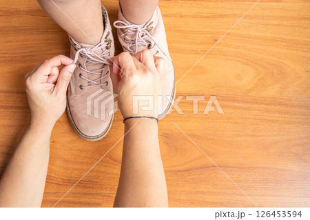 Father is helping his daughter to tie her shoelaces Father is helping his daughter to tie her shoelaces 126453594