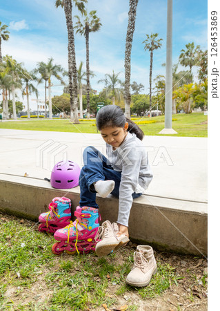 Little girl is putting on her roller skates Little girl is putting on her roller skates 126453869