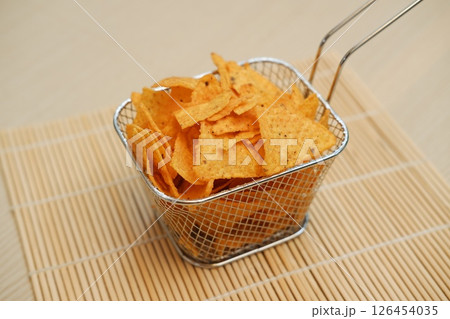 Golden tortilla chips in a metal basket Golden tortilla chips in a metal basket 126454035
