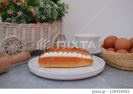 Delicious pastry with cream filling and almond flakes on a white plate. 126454083