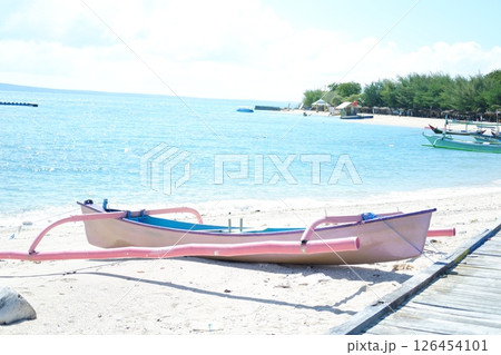 A blue fishing boat floating on the ocean under a bright sunny day 126454101