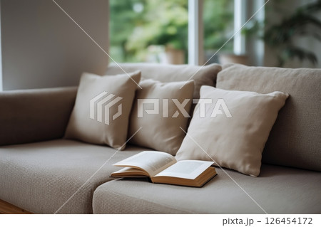 Beige Sofa with Pillows and Open Book in Bright Living Room 126454172