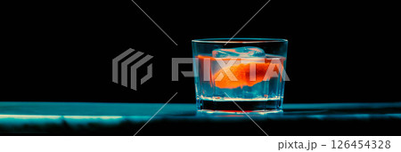 Classic old fashioned cocktail displayed in a rocks glass with a bright orange peel garnish. 126454328