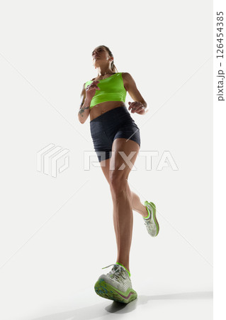 Portrait of confident female athlete in sprint pose from below showing power and focus 126454385