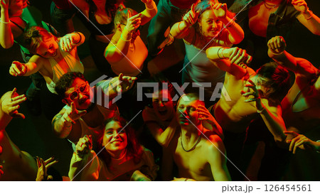 Group of people in colorful lighting, reaching out enthusiastically, creating vibrant energy. Group of people in colorful lighting, reaching out enthusiastically, creating vibrant energy. 126454561