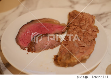 Sliced steak on a white plate, showing the texture and color. 126455151