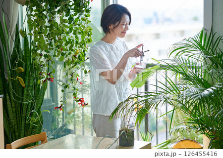 部屋の観葉植物に水をあげる女性 126455416