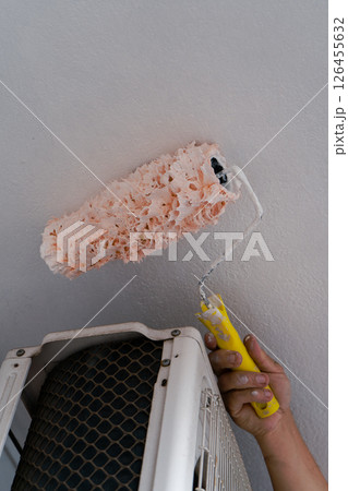 Painter using paint roller, painting ceiling near air conditioner 126455632